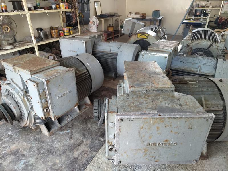 Several large Siemens motors on the workshop floor, with shelves of parts and tools behind them
